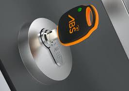 Close‑up of an ABS high‑security key inserted into a lock cylinder, showing the black and orange branded key head and precision‑engineered metal lock design.